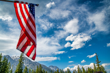 Wall Mural - American flag in Yellowstone National Park surrounded by trees and mountains.