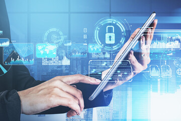 Poster - Businessman hand holds tablet device, blue hologram glowing digital information security interface. Concept of cyber security and data storage. Padlock and business symbols. Panoramic office