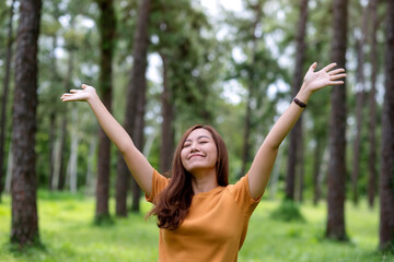 Wall Mural - Portrait image of a happy woman with arms rising in the park