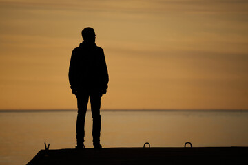 Sticker - man standing on rock looking straight. Nature and beauty concept. Orange sundown. Girl silhouette at sunset.