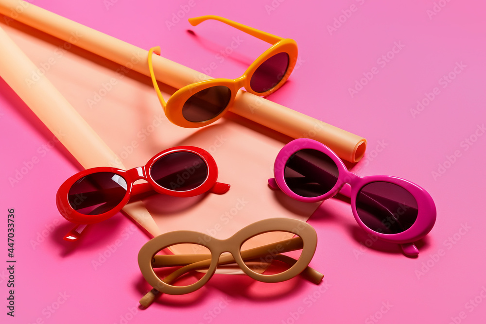 Stylish sunglasses and wrapping paper on color background