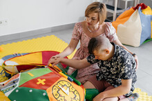 Children With Disability Getting Sensory Activity With Toys, Balls, Small Objects, Cerebral Palsy Boy Playing Calming Game, Training Fine Motor Skills. Rehabilitation Center With Therapist, Mother