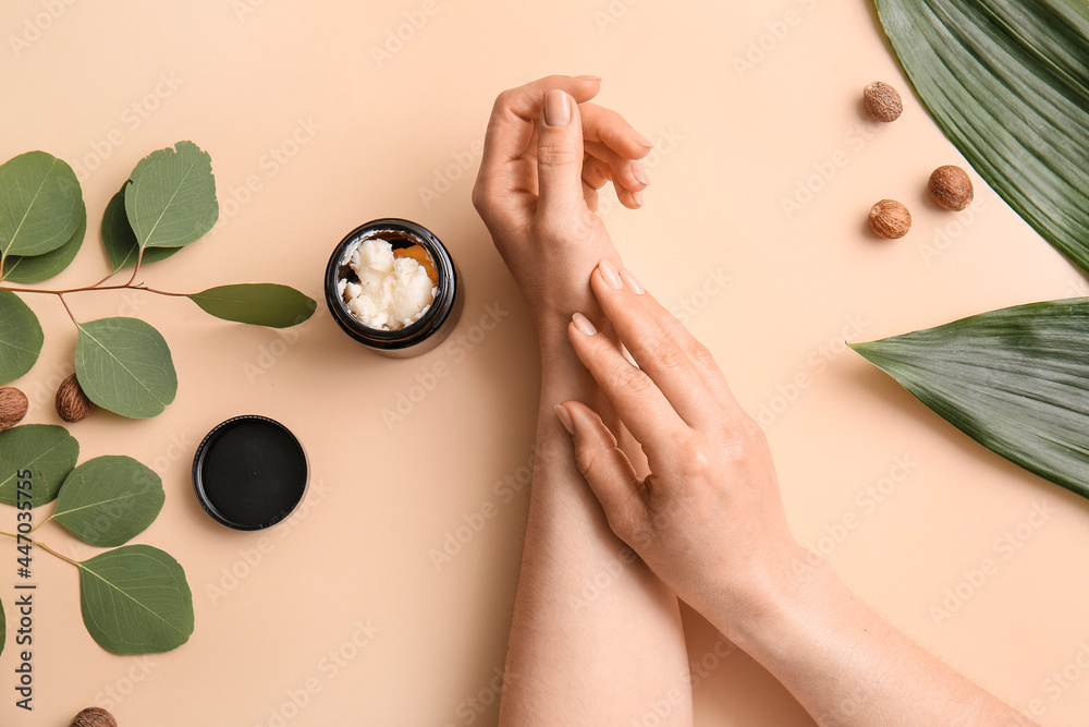 Female hands with jar of shea butter, nuts and leaves on color background - obrazy, fototapety, plakaty 