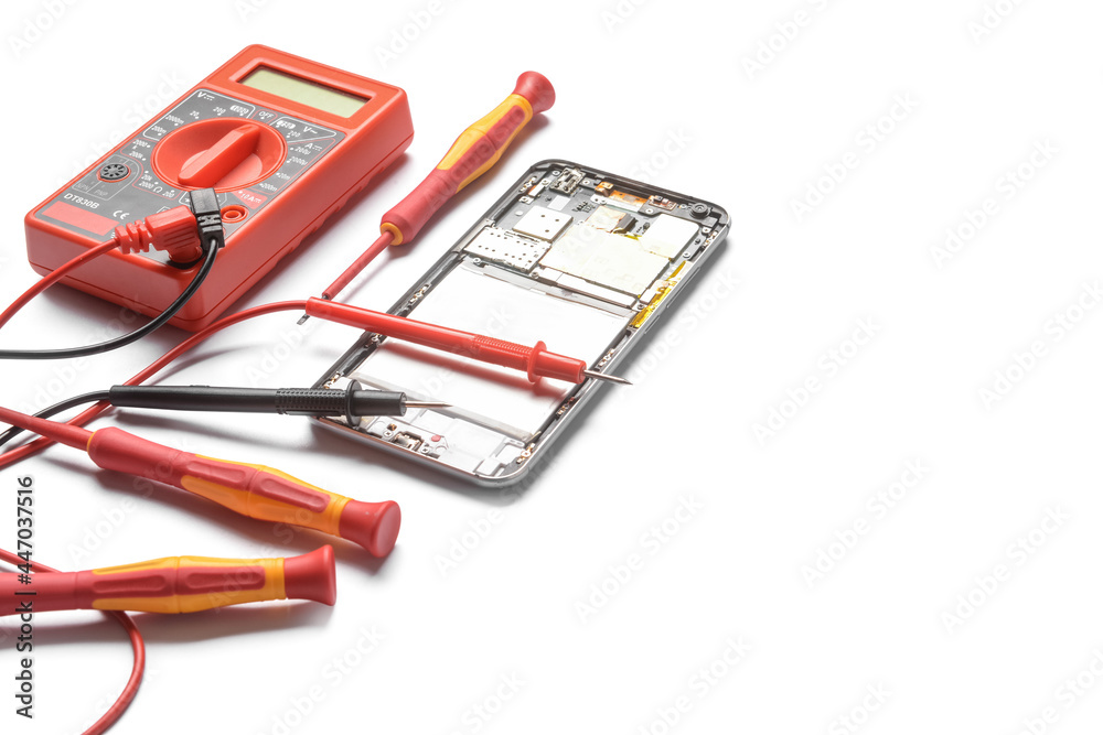 Disassembled mobile phone with multimeter on white background