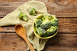 Bowl with frozen broccoli on wooden background