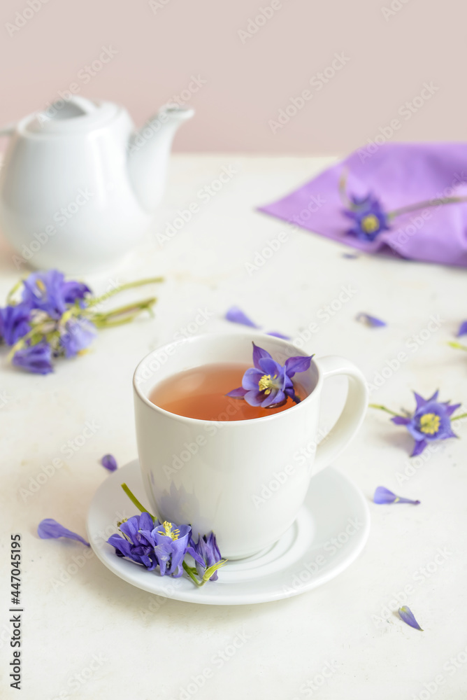 Cup of floral tea and flowers on light background