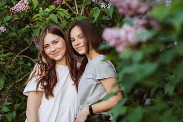 Wall Mural - Two young happy teenage girls are resting in the park on the green grass. Female friendship. Soft selective focus.