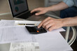 © fizkes - Male accountant sit indoor work with financial statements use calculator and laptop e-bank app, close up. Makes data entry and stats analysis, prepare report, manage family budget, accountancy concept