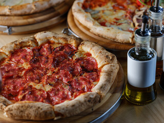 Wall Mural - Pizza bread with pepperoni meat and red tomatoes sauce with other Italian traditional pizza assorted mix on  restaurant background 