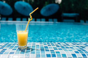 cocktail glass with cooling orange juice at the hotel's swimming pool for relaxation. Wine glass with an alcoholic drink by the water. Detox and wellness. Summer vacation concept.place for text