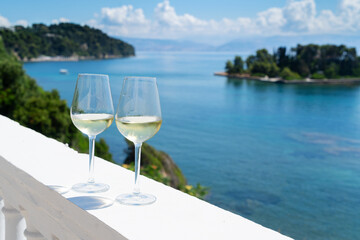 two glasses of white wine with corfu in background