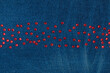 Red rhinestones lying in a line on worn denim. With space for design, text place.