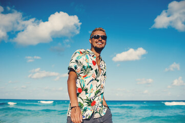 Young tourist man wearing hawaiian shirt at the sea or the ocean background. Travel vacation holiday. Man walking at the sea, enjoy tropical season