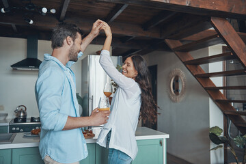 Sticker - Beautiful young couple smiling and dancing while spending time in the kitchen