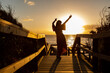 © Austockphoto - silhouette of young woman with arms in the air celebrate life against sunset at the beach