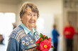 © Austockphoto - smiling elderly woman holding camellia flowers