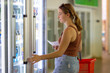 © Austockphoto - young woman with shopping basket shopping in small supermarket