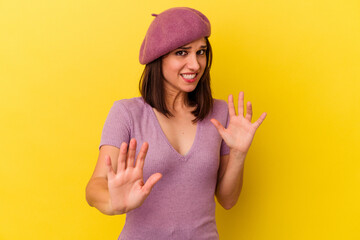 Young caucasian woman isolated on yellow background rejecting someone showing a gesture of disgust.