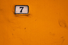 House Number 7 On Ceramic Table On Yellow Wall. Copy Space
