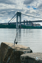 Poster - Closeup view of a fishing rod on the stone near the water in Palisades Interstate Park Alpine USA