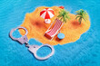 Handcuffs near miniature tropical island with palms and lounge on beach. Broken dreams escape justice or countries without extradition treaty concept
