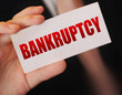 Bankruptcy on a card. Businessman holding a card with word Bankruptcy. Crisis business closing debts loss financial fiasko concept