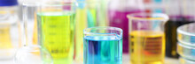 Flasks And Test Tubes With Multicolored Liquid Standing On Table In Laboratory