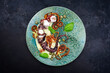 Modern style Italian polpo alla griglia su crema di patate with barbecued octopus, potato creme and fried chili onion rings as top view on a Nordic design plate with copy space