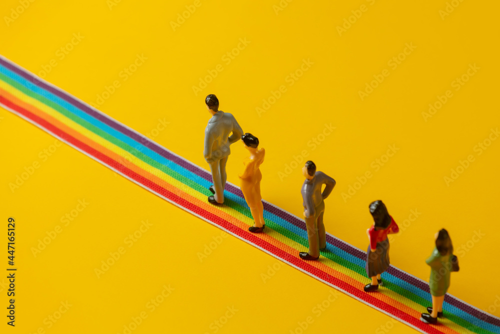 Group of figures of people stands on rainbow strip - obrazy, fototapety, plakaty 