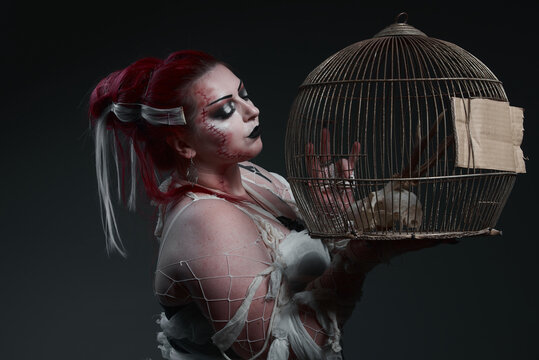 Frankenstein's bride holding and looking at the cage with animal skull, black background