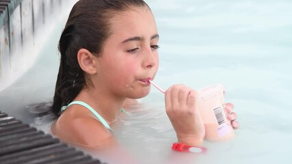 Wall Mural - Young girl relaxing sipping fruit juice in a natural pool