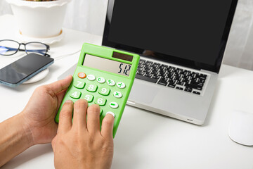 Accountant working and analyzing financial calculating with calculator and laptop computer income-expenditure at office desktop, Business financial and tax systems concept