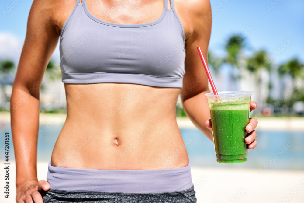 Green juice smoothie healthy detox diet weight loss fit woman drinking juice on outdoor beach summer lifestyle. Abs stomach and plastic cup. - obrazy, fototapety, plakaty 
