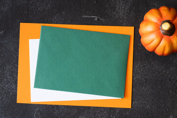 Wall Mural - Empty green paper for mock up template design and decorative pumpkin on dark background.