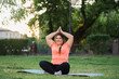 © golubovy - Park yoga. Meditation practice. Body positive. Nature harmony. Joyful smiling overweight obese woman in lotus pose exercising in summer weather landscape.