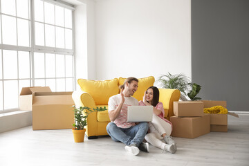 Wall Mural - Young couple using laptop in their new house on moving day