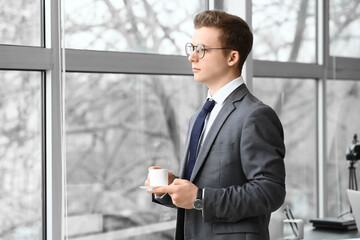 Wall Mural - Young man drinking coffee near window