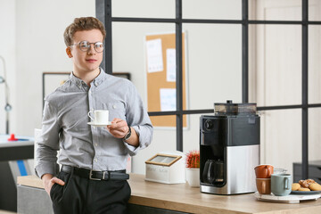 Wall Mural - Young man drinking coffee in office