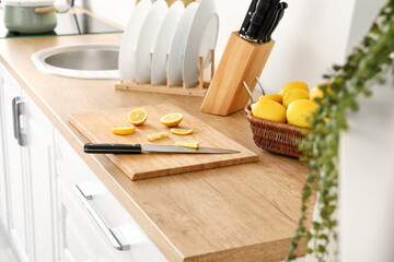 Board with knife and lemon on counter in kitchen