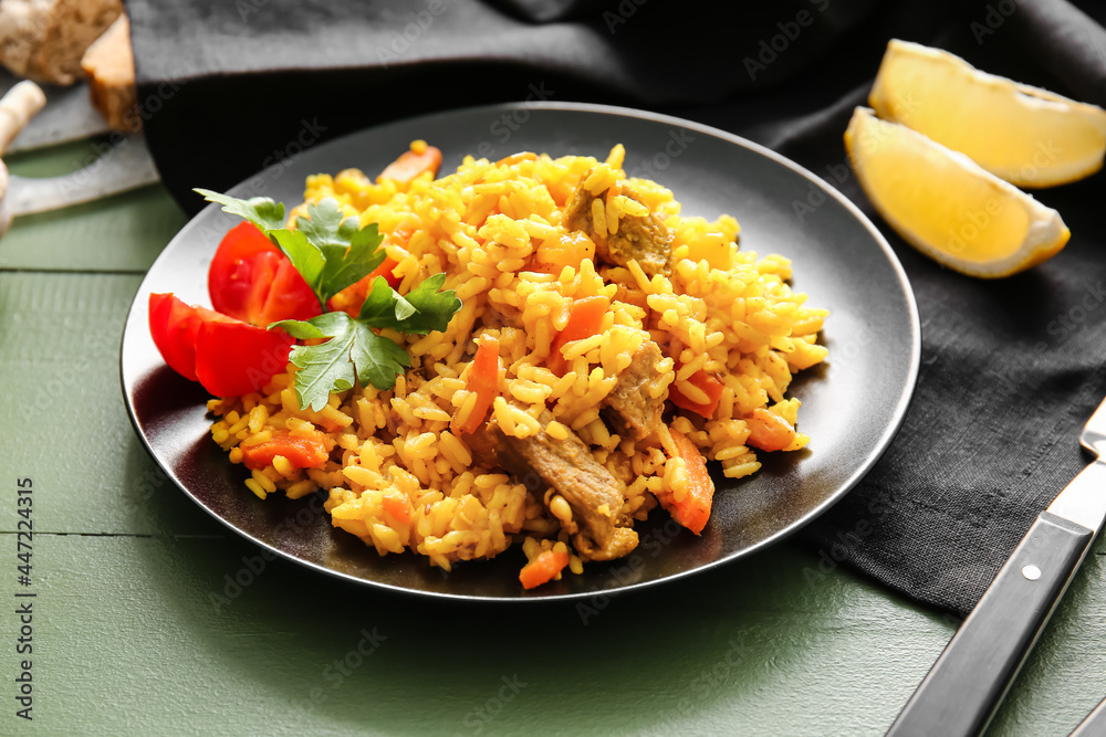 Plate with tasty pilaf on color wooden background