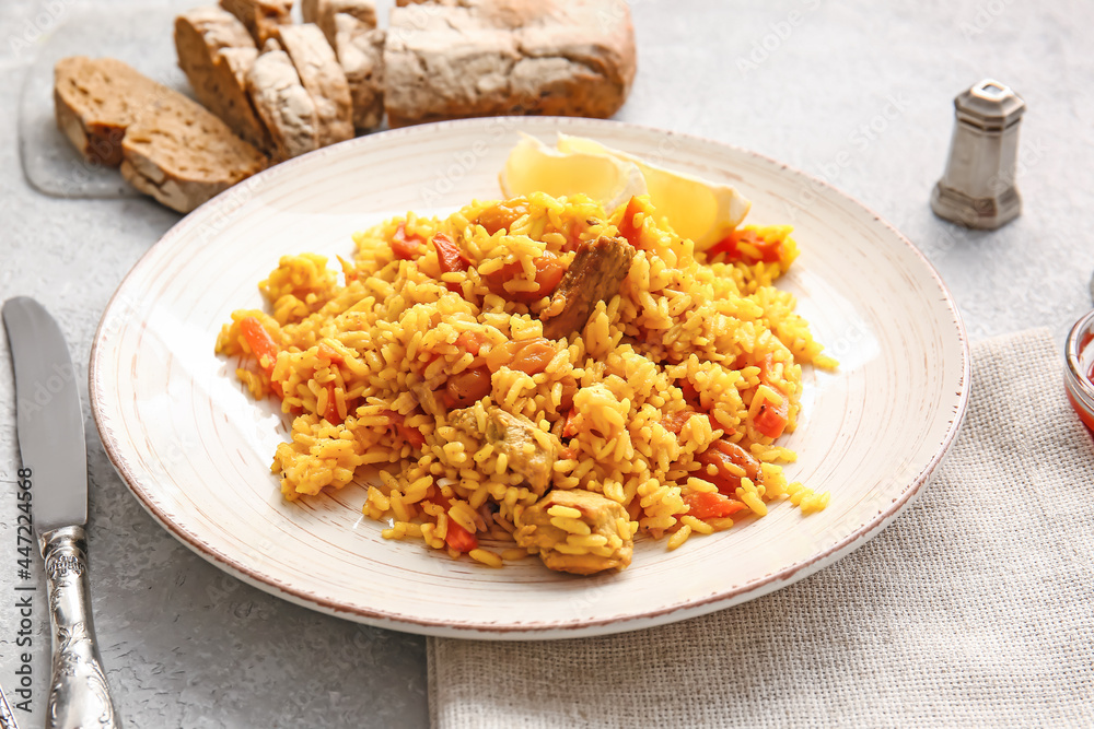 Plate with tasty pilaf on light background