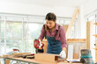 © godji10 - female carpenter uses a nail gun to assemble the wood in shop