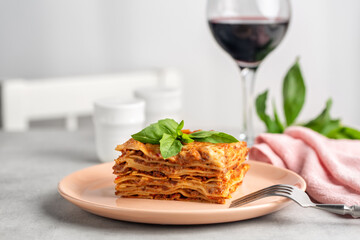 Canvas Print - Italian dinner. Meat lasagna decorated with basil leaves and red wine glass. Light table.