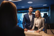 © Dusan Petkovic - A smiling business couple with positive vibes and energy standing at the hotel reception and checking in. Free weekend, relationship, business trip, recharging a battery