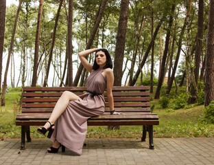 Wall Mural - young beautiful woman sitting on a park bench