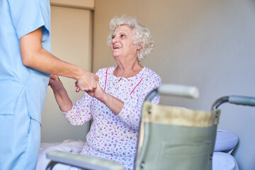 Carer helps elderly woman with dementia to get up