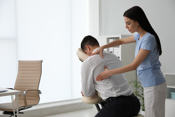 Canvas Print - Man receiving massage in modern chair indoors