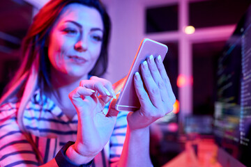 female coders working in office late at night and testing her new application on smartphone
