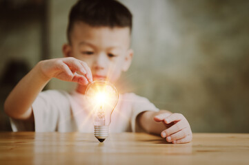 Wall Mural - Boy kid Child with a bright light bulb. Concept of Ideas for presenting new ideas Great inspiration and innovation new beginning.