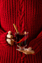 Woman wearing cozy red pullover holding a cup of mulled wine